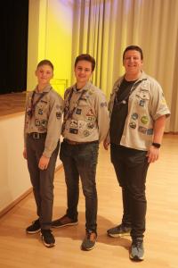 Das neue Stammesteam: Drei Personen im Alter zwischen 18 und 26 stehen in Kluft und Mit Halstuch in einer Halle.